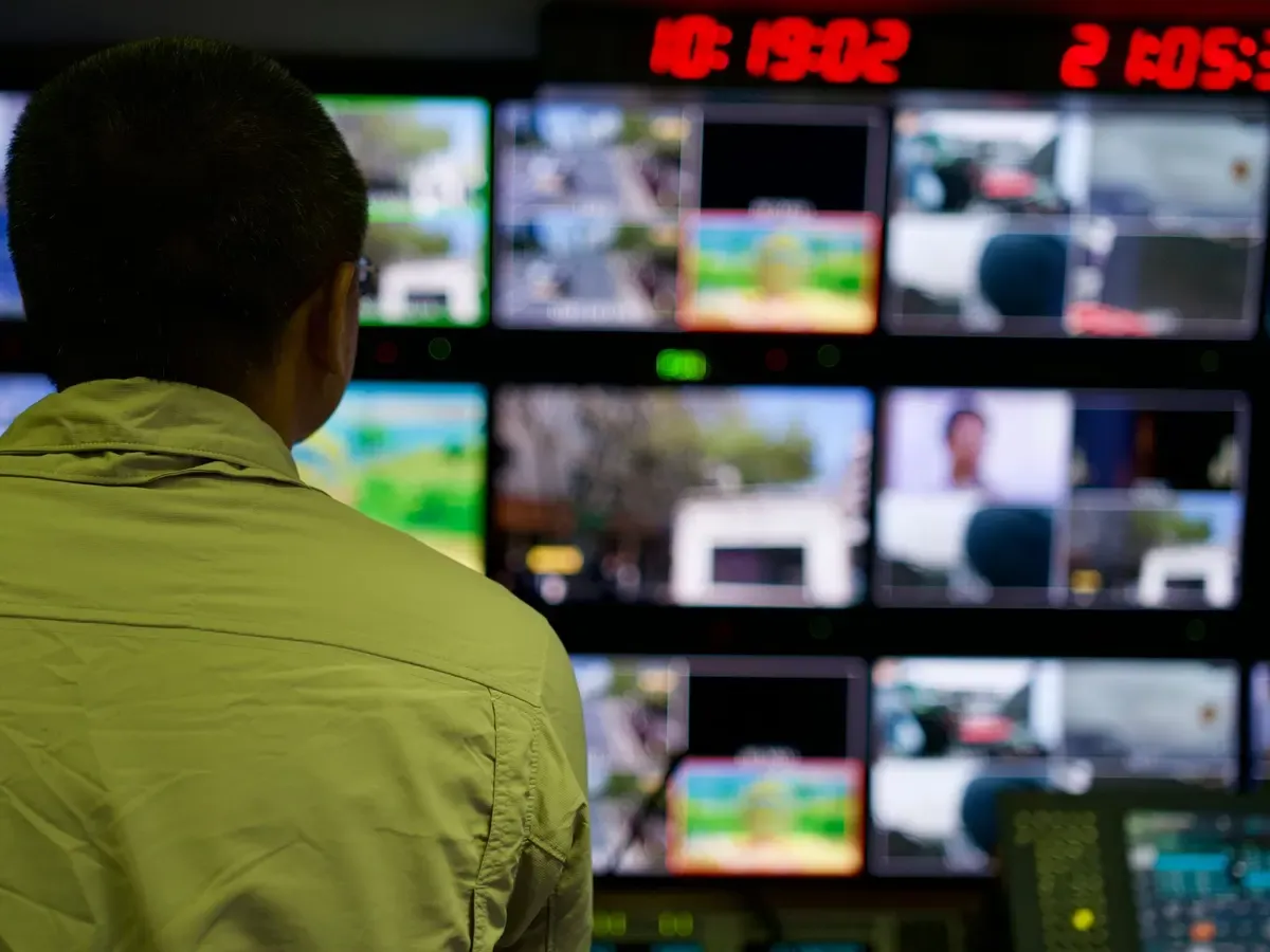 Operátor egy megfigyelő monitorfal előtt, több kamera élő képével